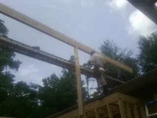 Carpenter setting a ridge beam over a new addition frame — Ice Dam Removal by Roofing Brothers in Santa Rosa Beach