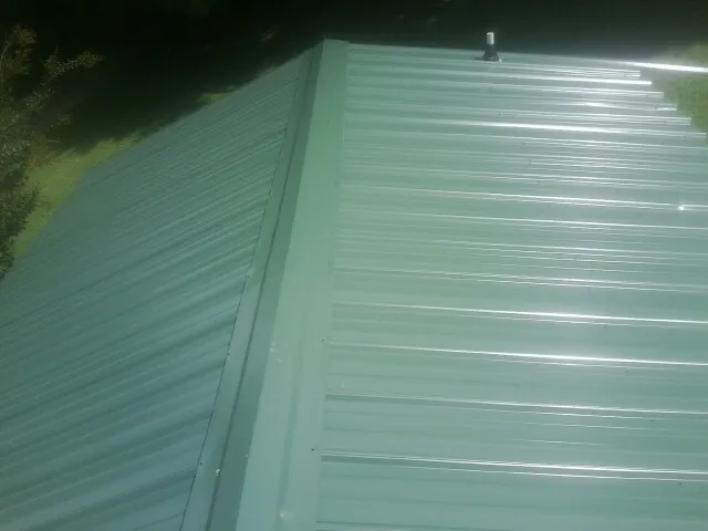 New green metal panels meeting at the ridge of a roof — Flat Roof Repair work by our crew in Santa Rosa Beach