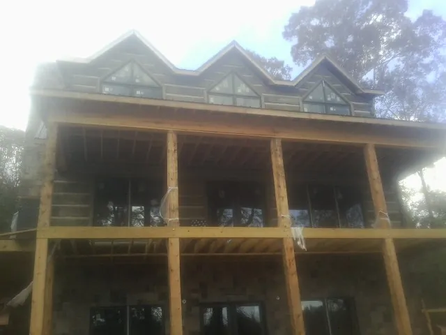 Dormers and porch framing on a large log home under construction — Roof Coating work by our crew in Santa Rosa Beach