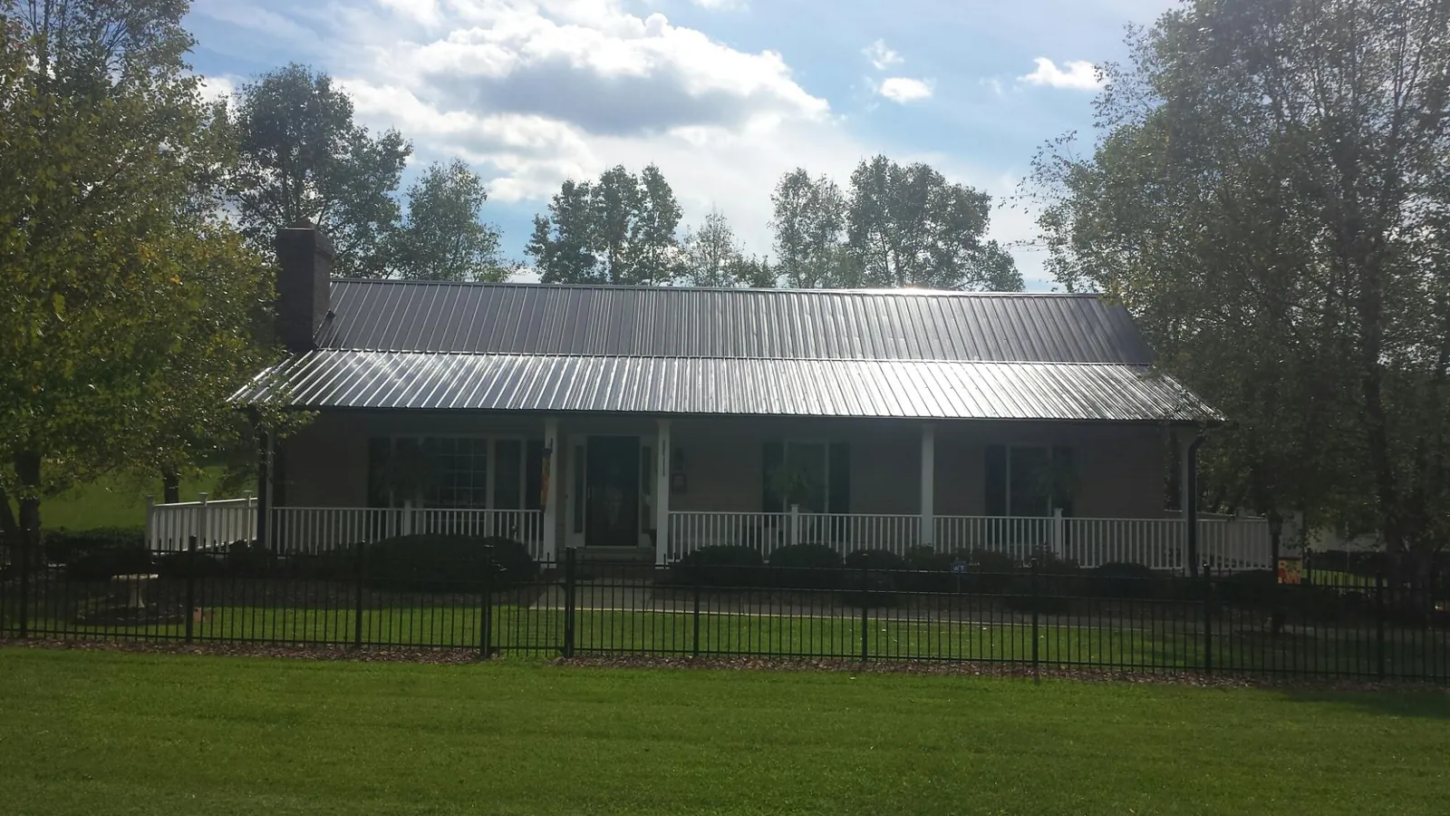 Gray metal roof on a brick ranch with a full width front porch — Gutter Guard Installation work by our crew in Santa Rosa Beach