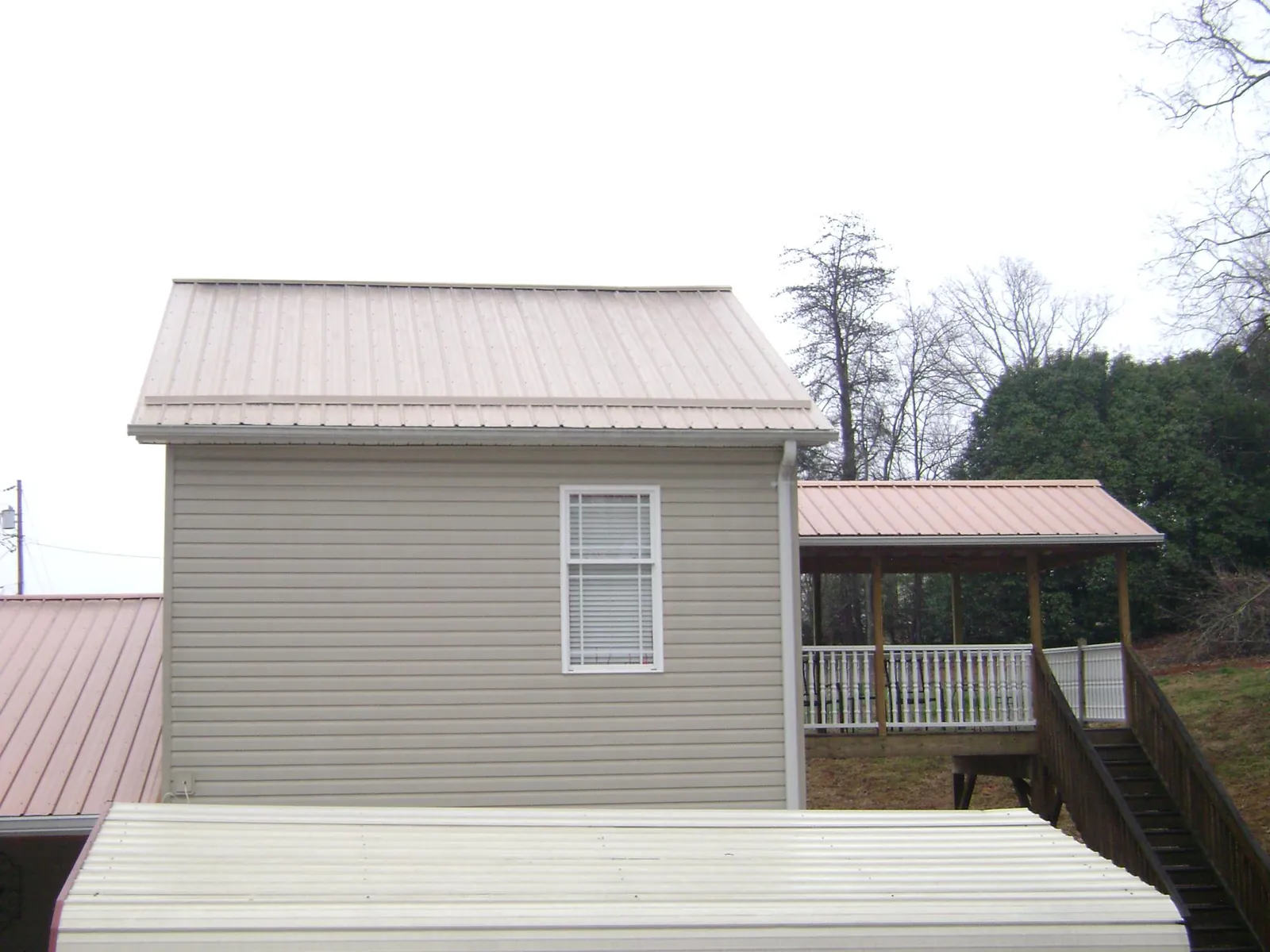 Tan metal roofs on a two story addition and attached porch, from a Roof Replacement job in Santa Rosa Beach