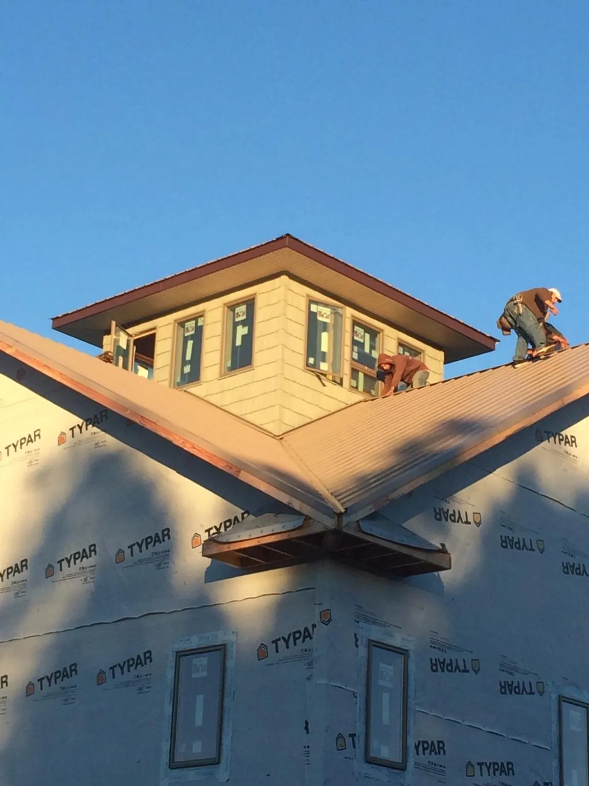 Roofers working around a rooftop cupola on a new metal roof at sunset — Roof Waterproofing in Santa Rosa Beach by Roofing Brothers